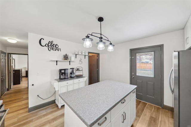 kitchen featuring light wood finished floors, freestanding refrigerator, and white cabinetry