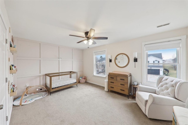 bedroom with light carpet, visible vents, and a ceiling fan