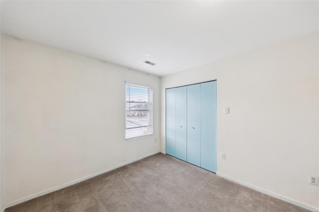 unfurnished bedroom with a closet, carpet flooring, visible vents, and baseboards