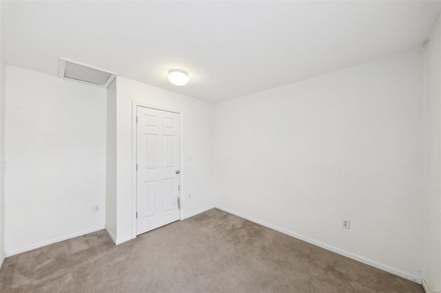 empty room with attic access, carpet floors, and baseboards