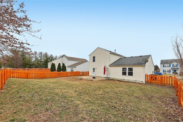 rear view of house with a fenced backyard and a yard