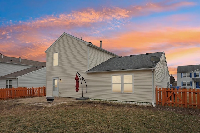 rear view of property with a yard, a shingled roof, a patio, and fence