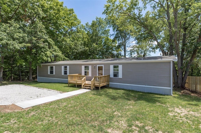 rear view of house featuring a yard, a wooden deck, and fence