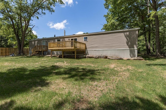 back of property with a lawn, a deck, and fence