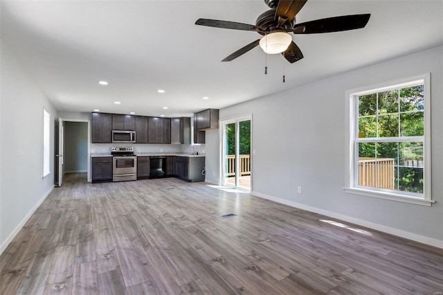 unfurnished living room with recessed lighting, light wood-style floors, a sink, ceiling fan, and baseboards