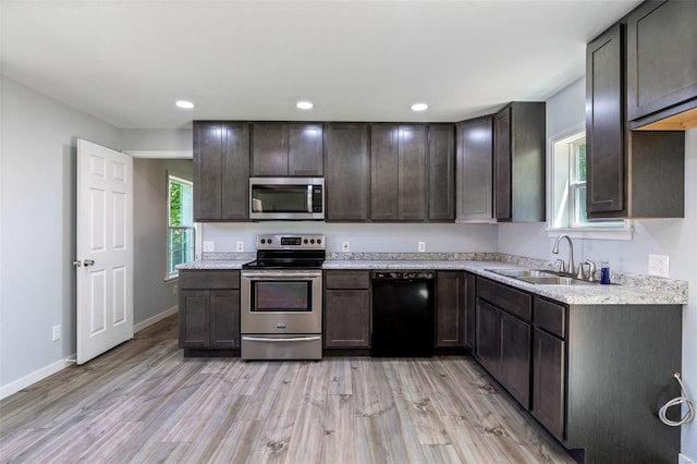 kitchen with light wood-style flooring, a sink, light countertops, appliances with stainless steel finishes, and dark brown cabinets