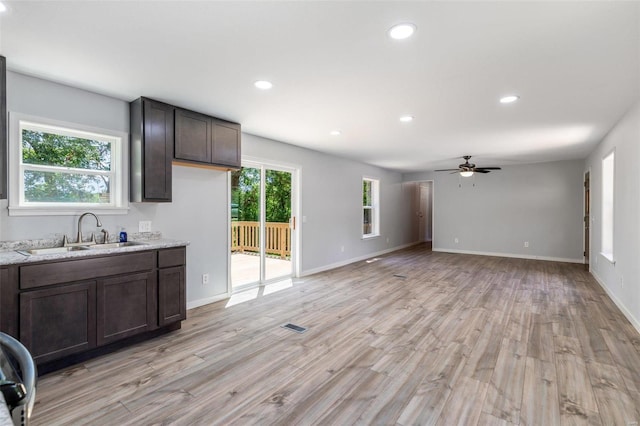 kitchen featuring dark brown cabinetry, light wood-style flooring, a sink, and recessed lighting