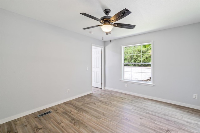 empty room featuring a ceiling fan, light wood-type flooring, visible vents, and baseboards