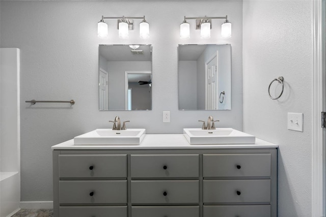 bathroom featuring double vanity, visible vents, baseboards, and a sink