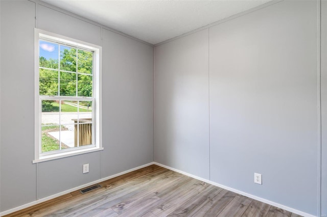 spare room featuring a wealth of natural light, visible vents, light wood-style flooring, and a textured ceiling