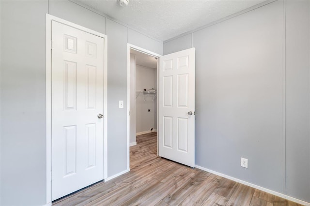 unfurnished bedroom with light wood finished floors, baseboards, and a textured ceiling