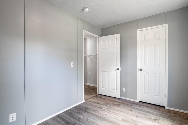 unfurnished bedroom featuring light wood finished floors, baseboards, and a textured ceiling