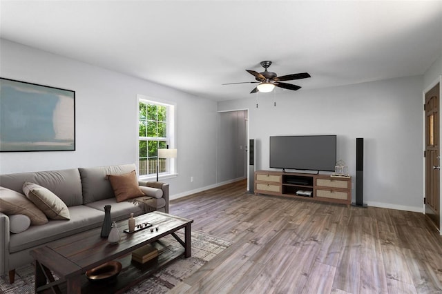 living area with a ceiling fan, baseboards, and light wood finished floors