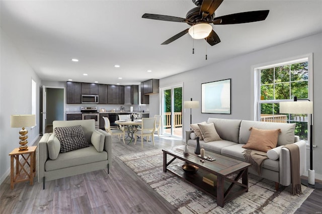 living area with baseboards, light wood-type flooring, a ceiling fan, and recessed lighting