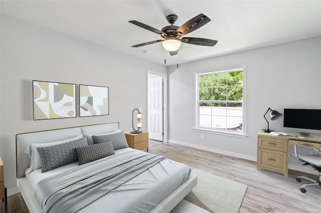 bedroom with light wood-type flooring, a ceiling fan, and baseboards