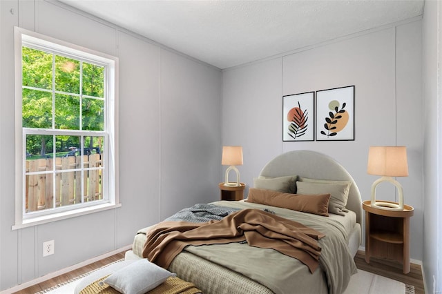 bedroom with a textured ceiling, a decorative wall, and wood finished floors