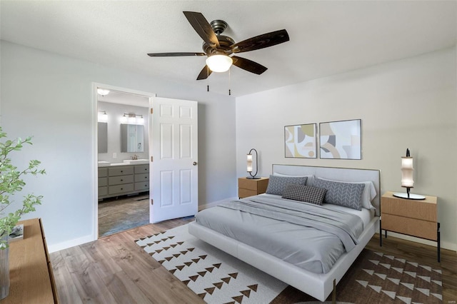 bedroom with a sink, ensuite bathroom, wood finished floors, and baseboards