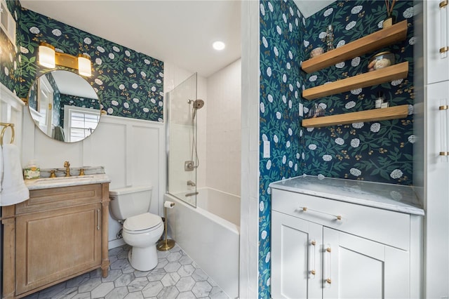 bathroom featuring a wainscoted wall, toilet, wallpapered walls, shower / bath combination, and vanity