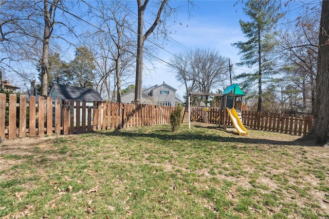 view of yard featuring an outdoor structure, a playground, and a fenced backyard