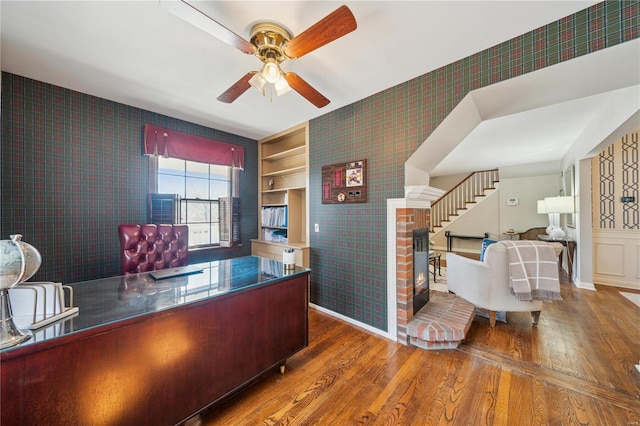 home office with wallpapered walls, wood finished floors, and a ceiling fan