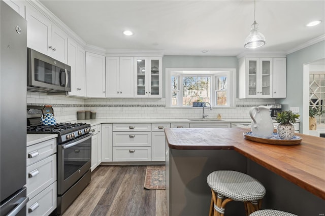 kitchen with dark wood-style floors, wooden counters, a sink, appliances with stainless steel finishes, and white cabinetry