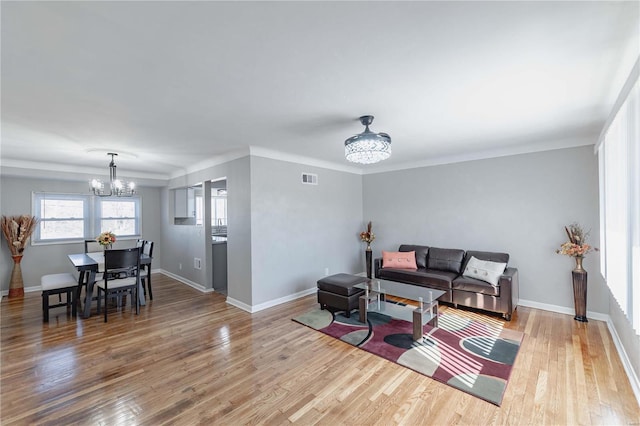 living room with an inviting chandelier, baseboards, visible vents, and wood finished floors