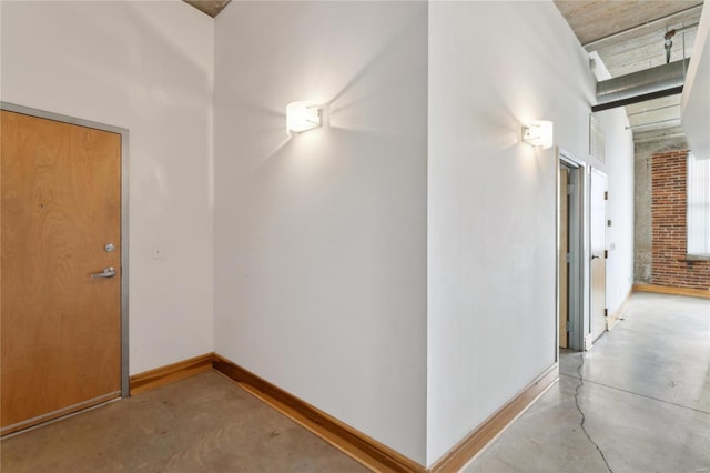 hallway with concrete flooring and baseboards