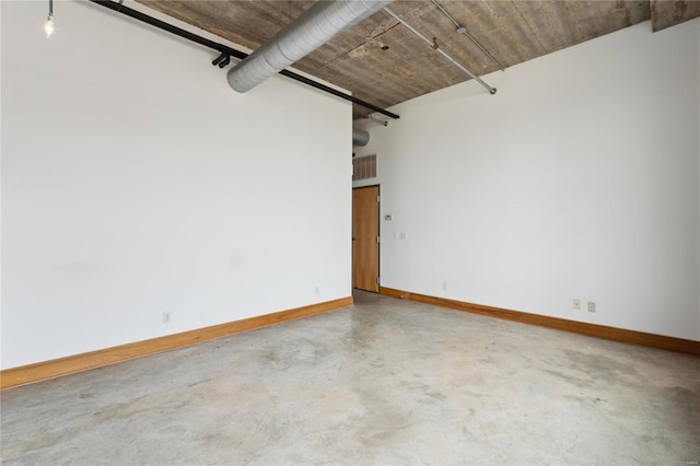 unfurnished room featuring finished concrete flooring and baseboards