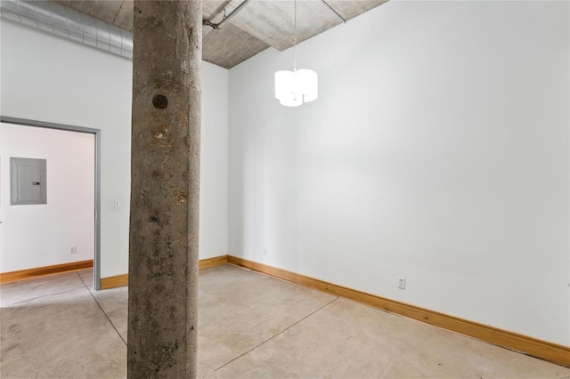 spare room with finished concrete floors, electric panel, and baseboards