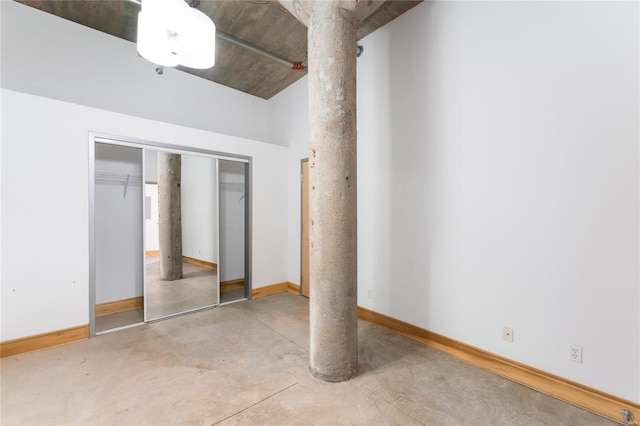 unfurnished bedroom with ornate columns, concrete floors, baseboards, and a closet