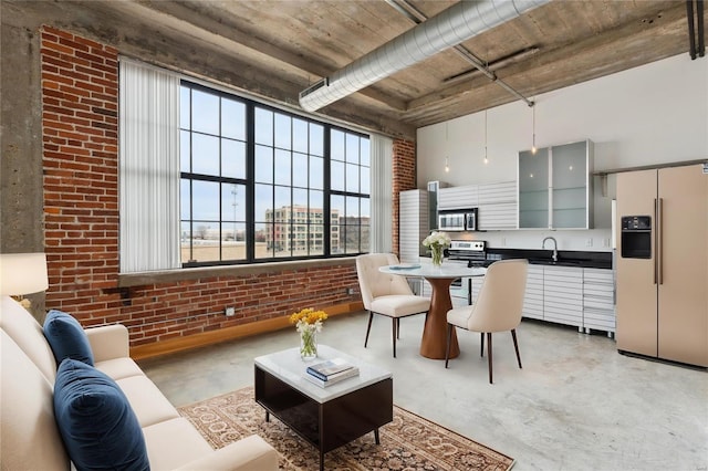 kitchen with concrete flooring, brick wall, stainless steel microwave, and refrigerator with ice dispenser