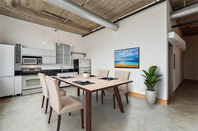 dining room with concrete flooring, a high ceiling, and baseboards