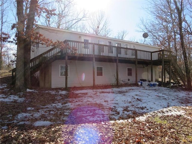 snow covered back of property with stairway and a wooden deck