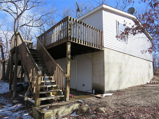 rear view of property featuring stairs and a wooden deck