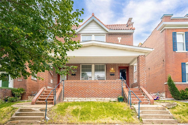 view of front facade featuring stairs, brick siding, and covered porch