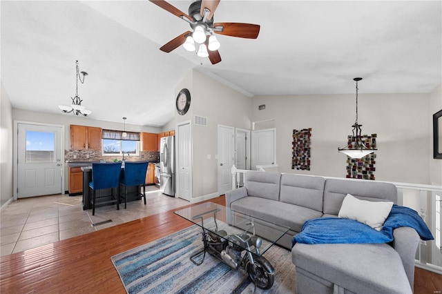 living area featuring lofted ceiling, baseboards, visible vents, and light wood finished floors