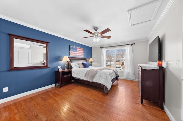 bedroom featuring ceiling fan, wood finished floors, baseboards, ornamental molding, and attic access