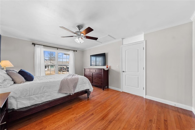 bedroom with crown molding, light wood finished floors, attic access, ceiling fan, and baseboards