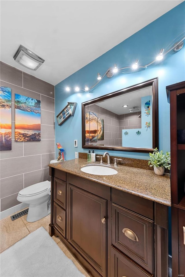 full bathroom with toilet, visible vents, tile walls, vanity, and tile patterned floors