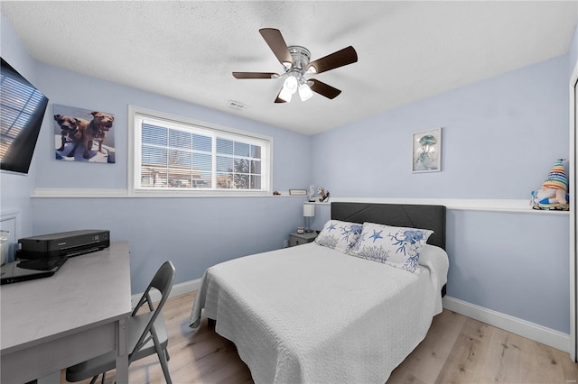 bedroom with baseboards, visible vents, ceiling fan, a textured ceiling, and light wood-type flooring