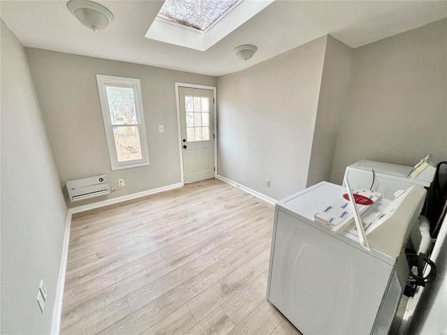 laundry area with baseboards, light wood finished floors, laundry area, a skylight, and washer and dryer