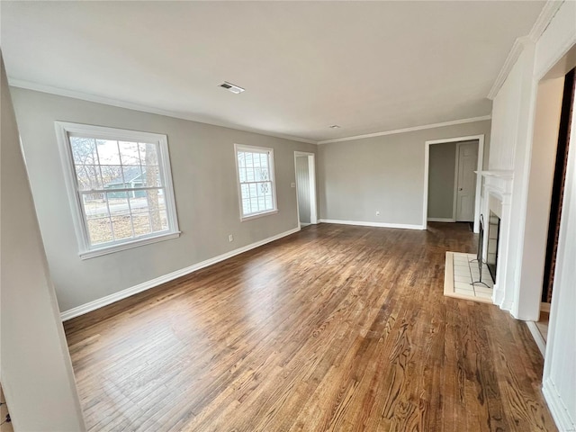 unfurnished living room featuring visible vents, a fireplace with raised hearth, baseboards, ornamental molding, and dark wood-style flooring