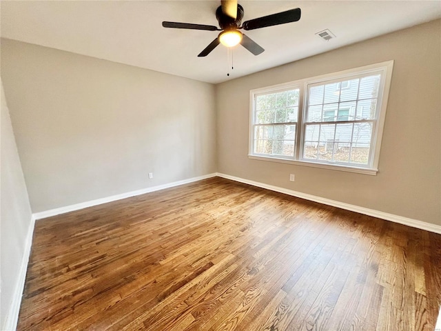 empty room with visible vents, baseboards, hardwood / wood-style floors, and a ceiling fan