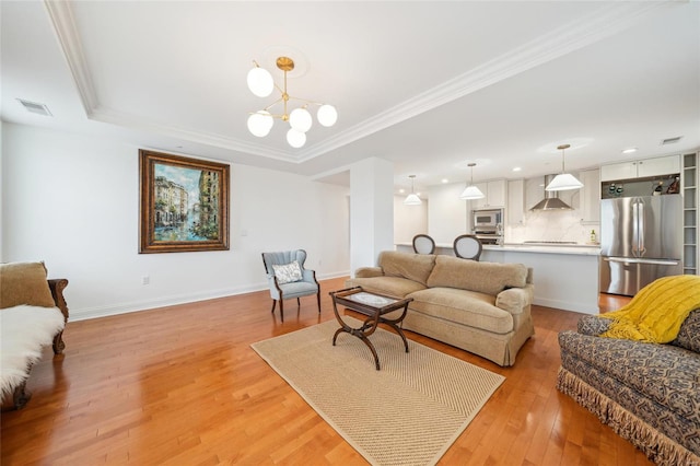 living area with a notable chandelier, visible vents, baseboards, light wood finished floors, and crown molding