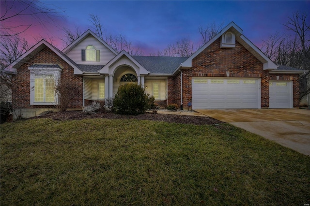 traditional-style home with a garage, driveway, a shingled roof, a lawn, and brick siding