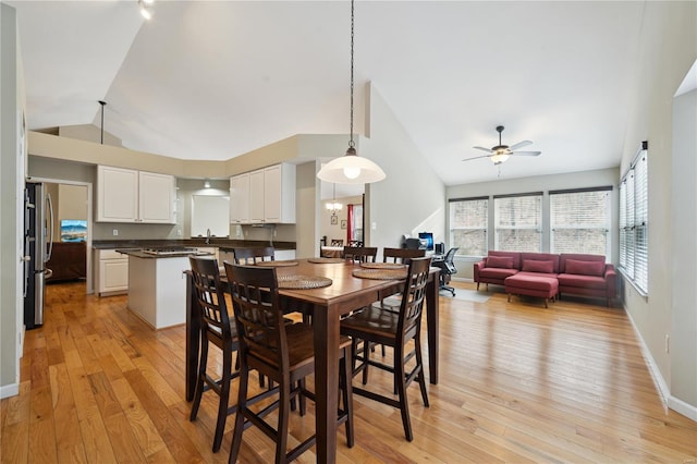 dining room featuring baseboards, vaulted ceiling, light wood finished floors, and ceiling fan