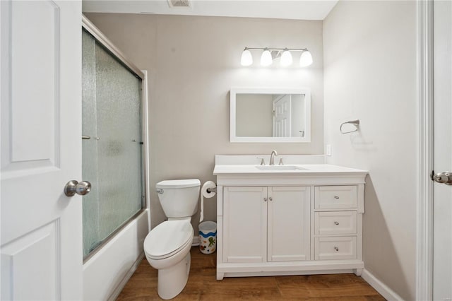 bathroom featuring toilet, bath / shower combo with glass door, wood finished floors, vanity, and baseboards