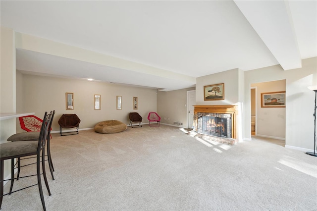 unfurnished living room with carpet, beamed ceiling, a lit fireplace, and baseboards