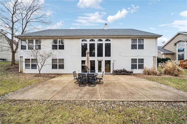 back of property with a patio area, a chimney, and roof with shingles