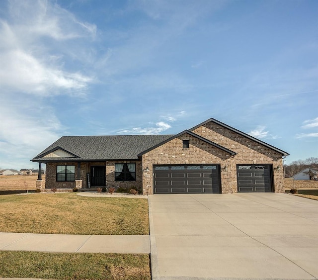 view of front of property with driveway, a shingled roof, an attached garage, a front lawn, and brick siding